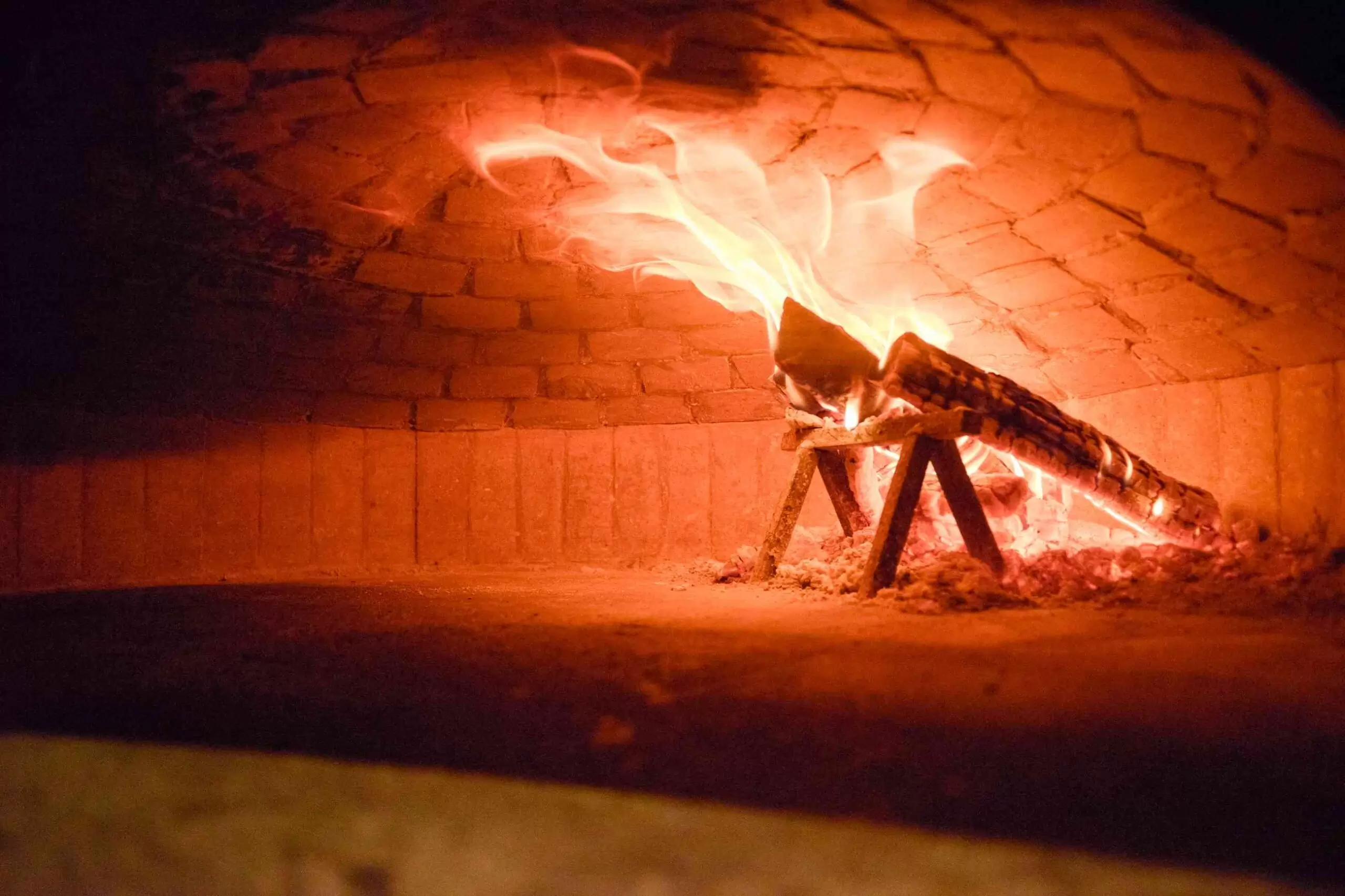 Brick wood-fired oven interior with live fire